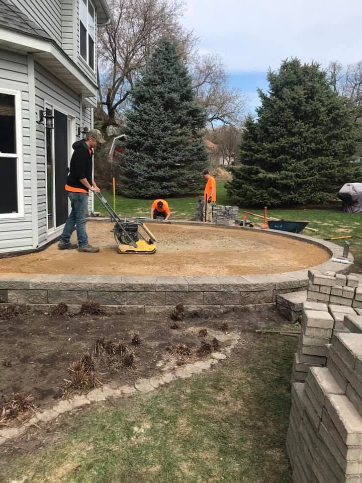 A man is working on a patio in front of a house.
