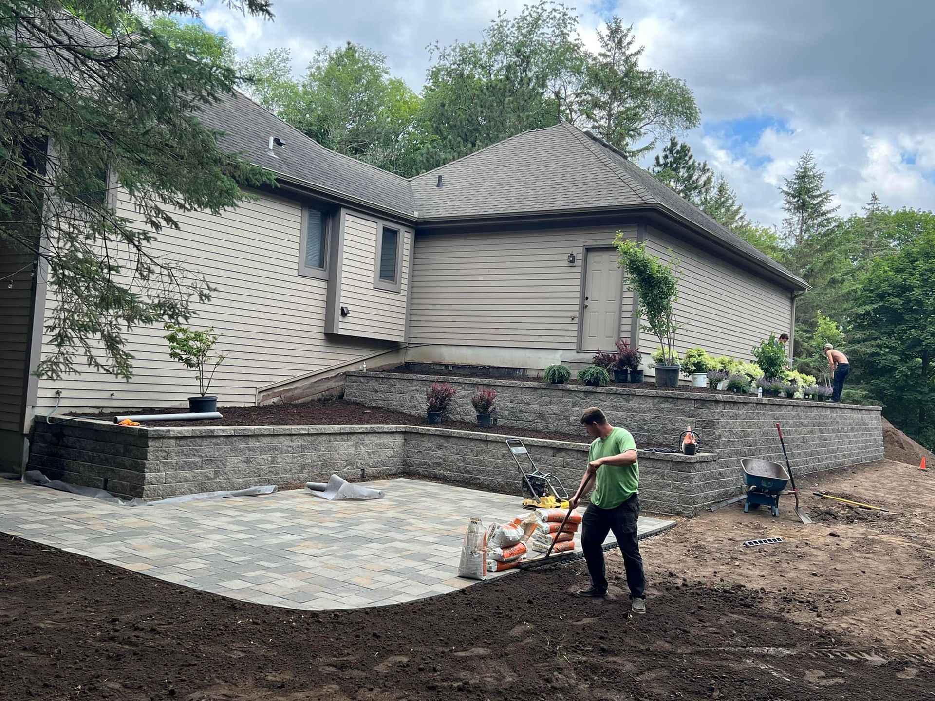 A man is working on a patio in front of a house.