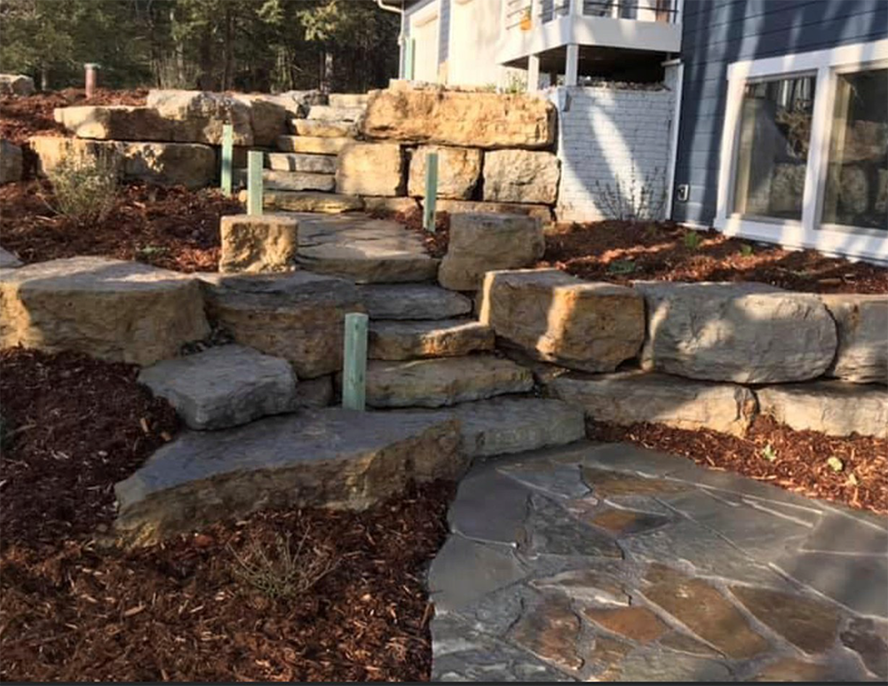 A stone walkway leading to a house surrounded by rocks.