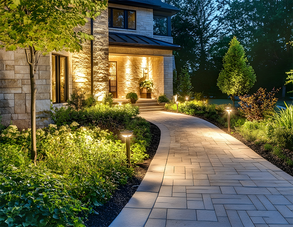 A brick walkway leading to a house is lit up at night