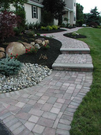 A brick walkway with steps leading to a house.