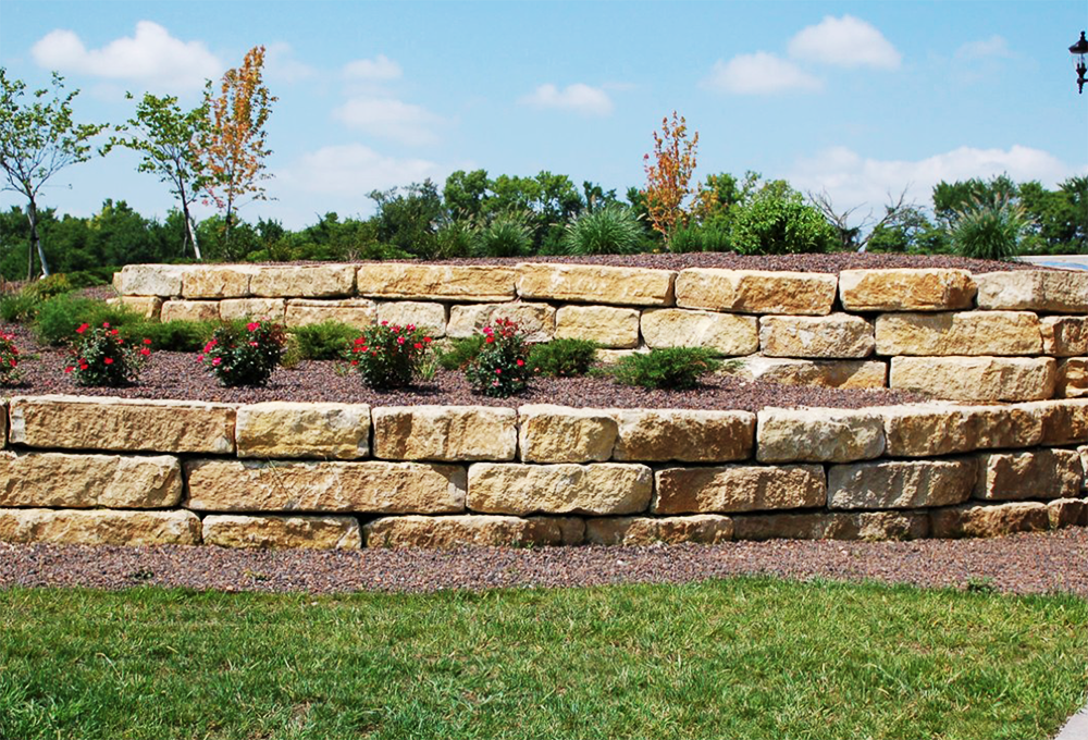 A large stone wall surrounds a lush green field.