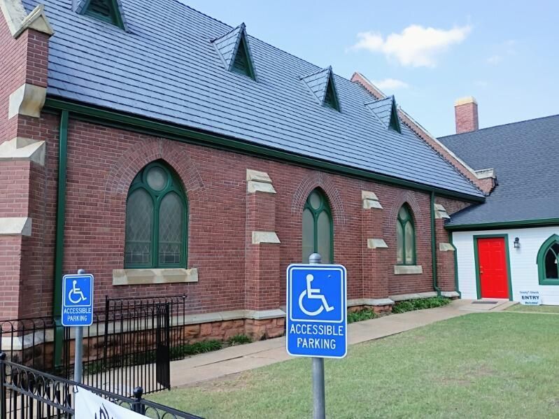 Brick church exterior with handicap parking signs and accessible entrance ramp