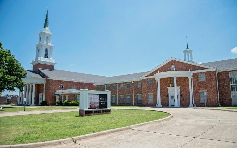 Brick church building with a tall steeple under a clear blue sky.