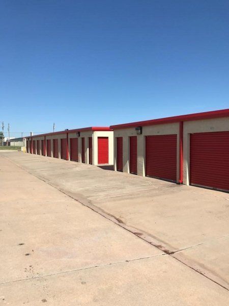Storage units with red doors and trim under a blue sky.
