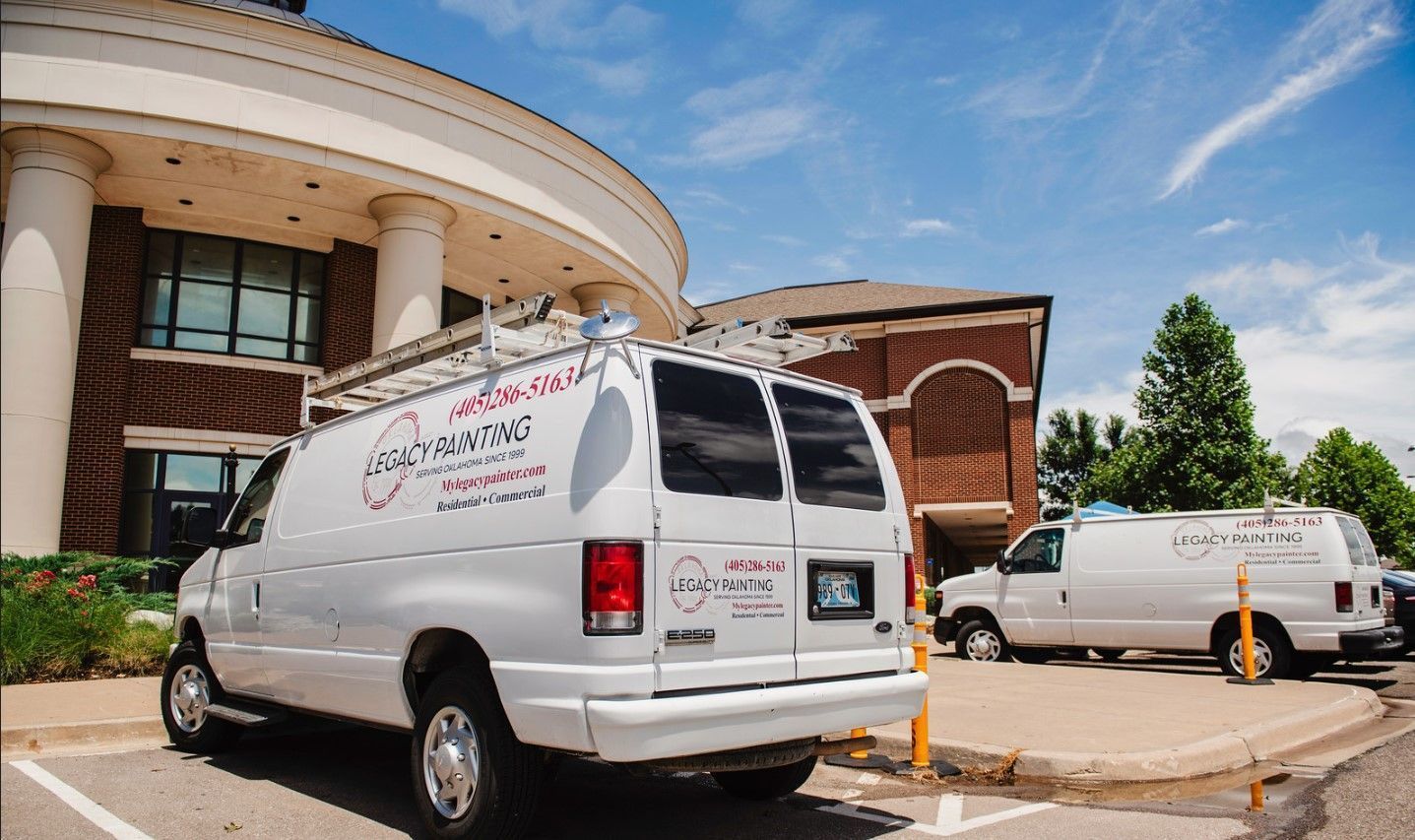 White service vans parked outside a building with columns, under a blue sky.