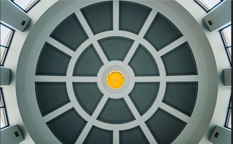 Gray and white domed ceiling with radial grid design and central yellow light fixture.