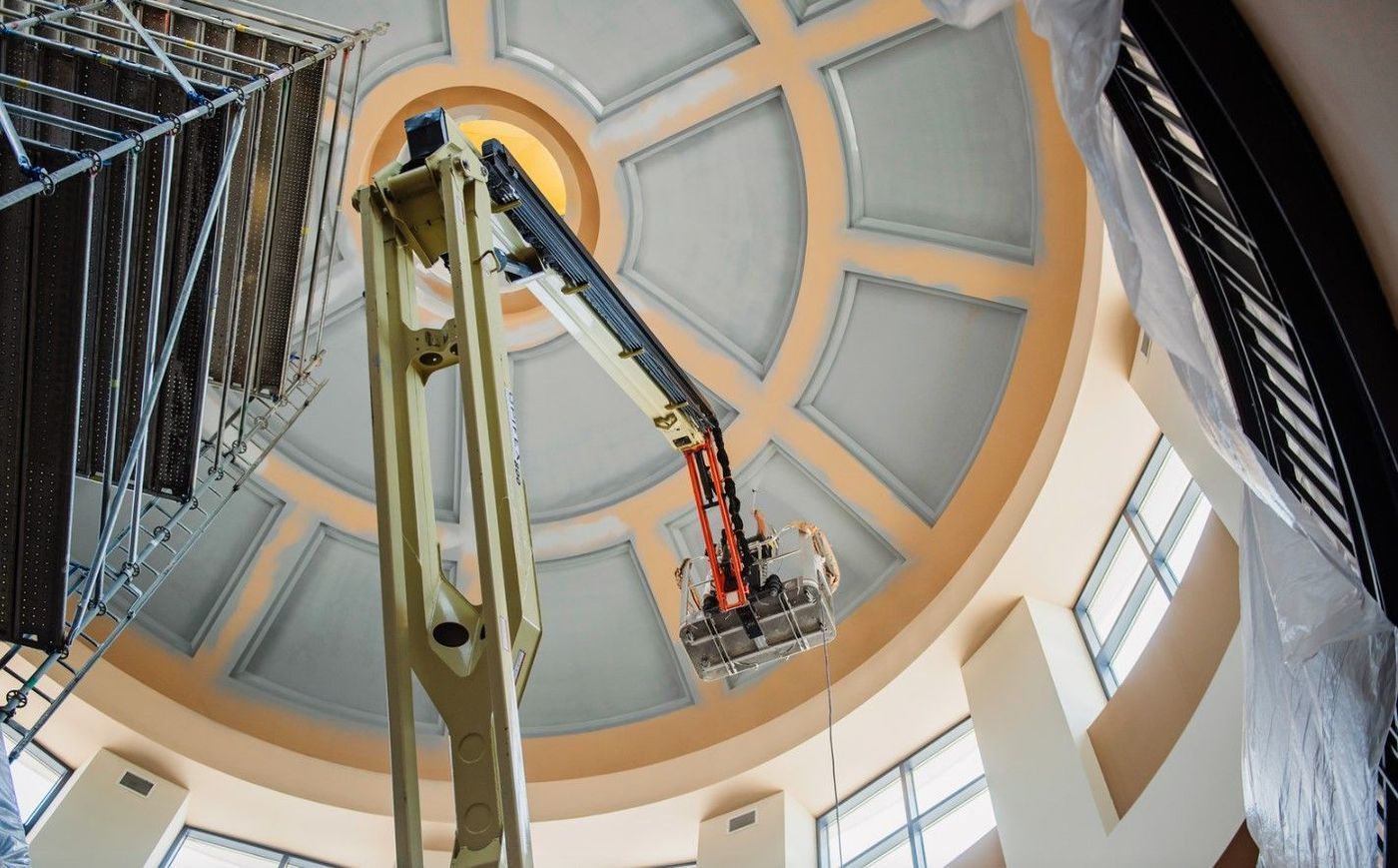 Construction worker in a lift inspecting a domed ceiling.