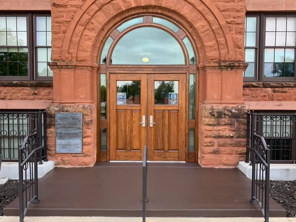 Entrance of a brick building with arched doorway and wooden double doors.