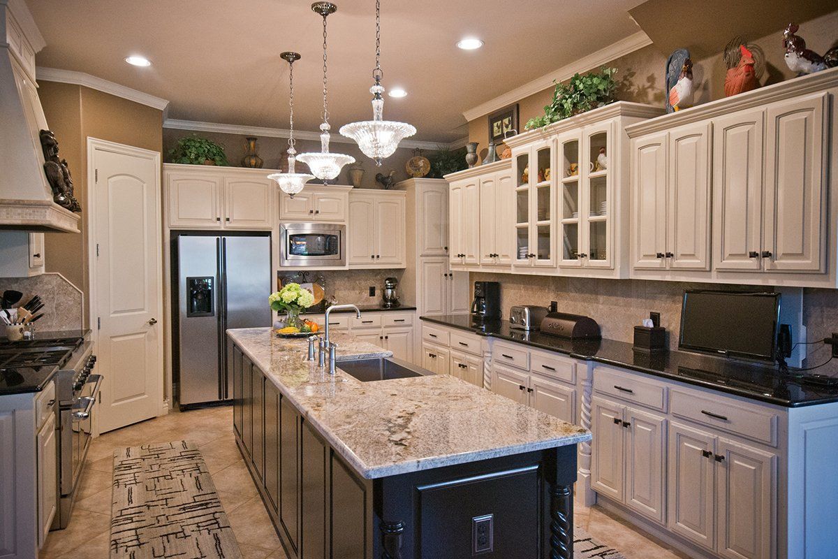 Spacious kitchen with white cabinets, stainless steel appliances, large island with granite countertop.