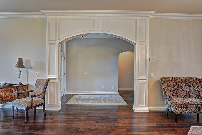 Interior view: archway with white trim, dark wood floor, light gray walls, furniture in the foreground.
