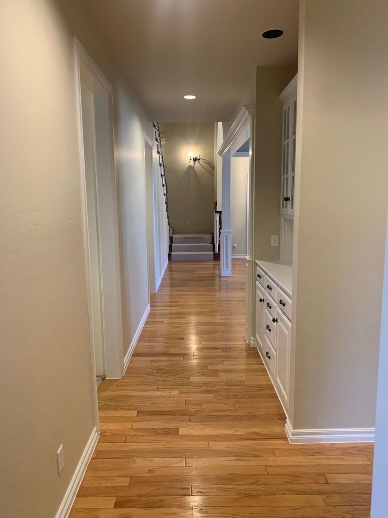 Long hallway with wood floor, white trim, and beige walls.