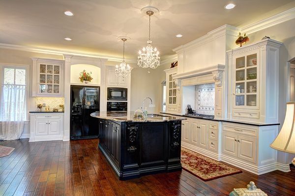 Elegant kitchen with black island, white cabinets, and hardwood floors.