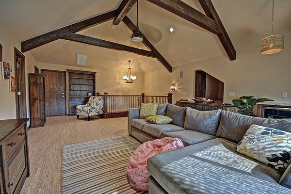 Living room with vaulted ceiling, exposed beams, sectional sofa, rug, and loft area.