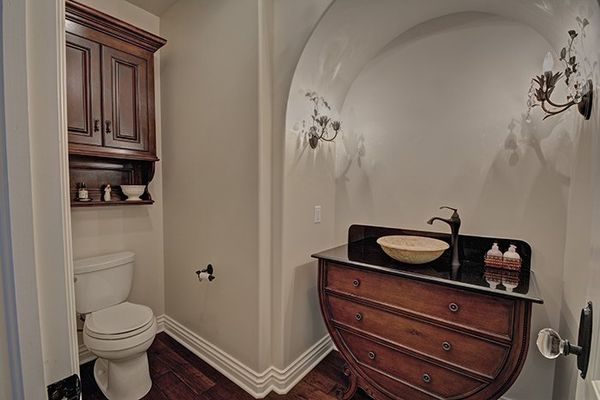 A powder room with a curved vanity, dark wood cabinetry, and a toilet.