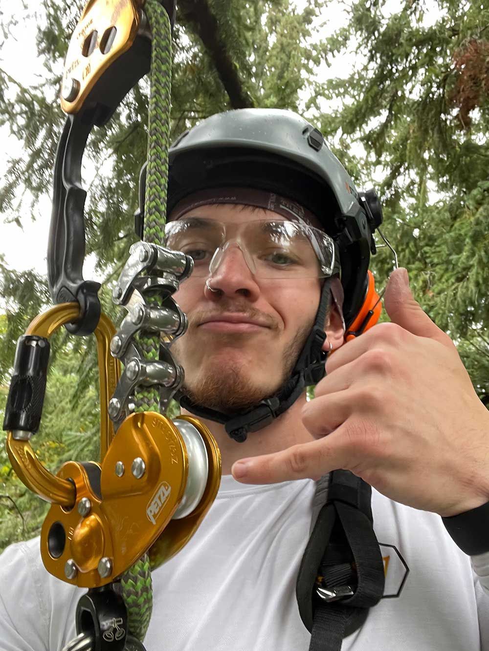 A man wearing a helmet and goggles is making a thumbs up sign.