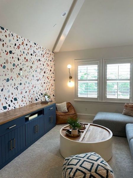 Living room with terrazzo accent wall, blue cabinets, and round coffee table.