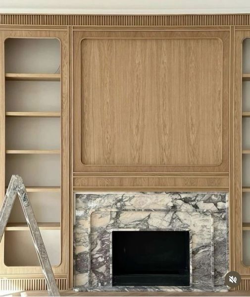 Built-in oak shelving and fireplace surround with marble hearth and black firebox.