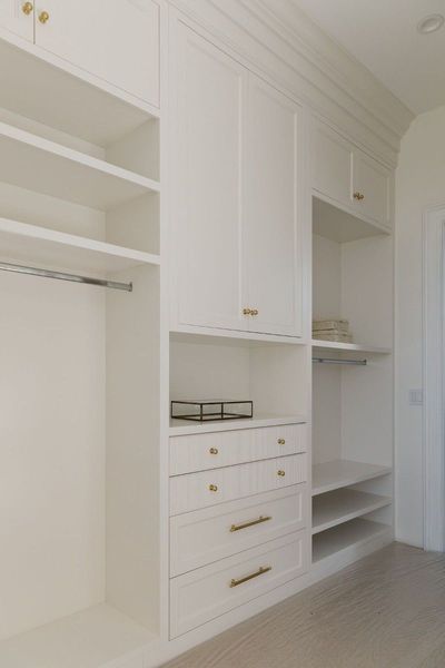 White custom closet with shelves, drawers, and hanging rods.