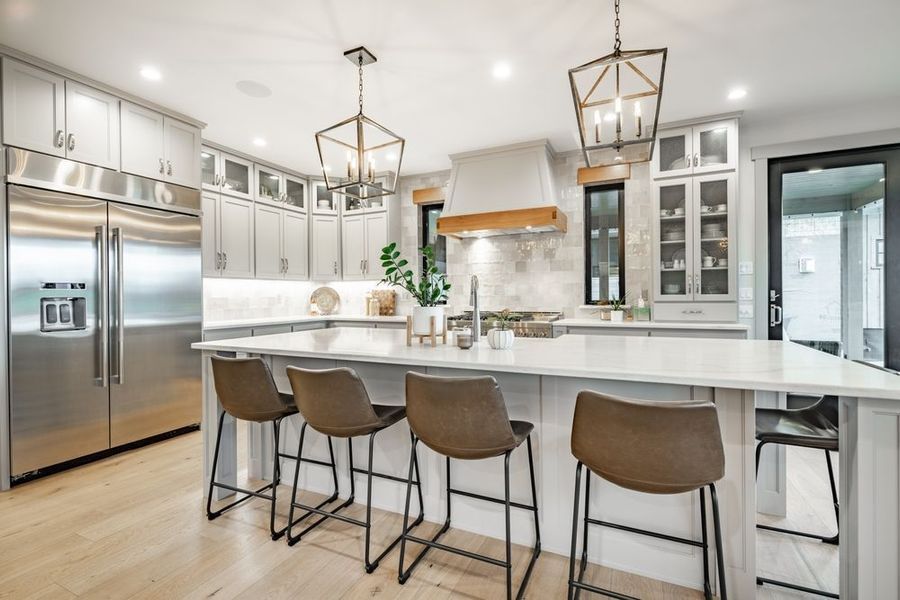 Modern kitchen with stainless steel appliances, white island, and gray cabinets.