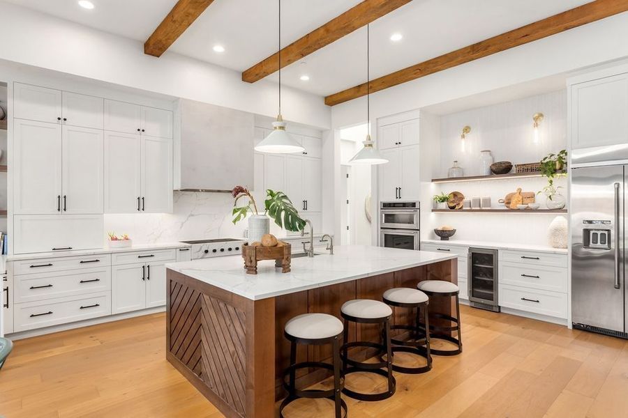 Modern kitchen with white cabinets, wood island, and stainless steel appliances.