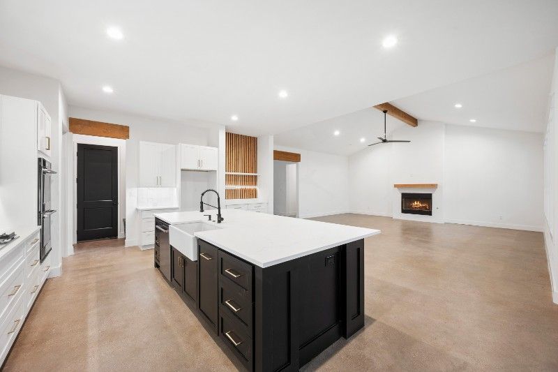 Modern kitchen with dark island, white countertops, and fireplace.