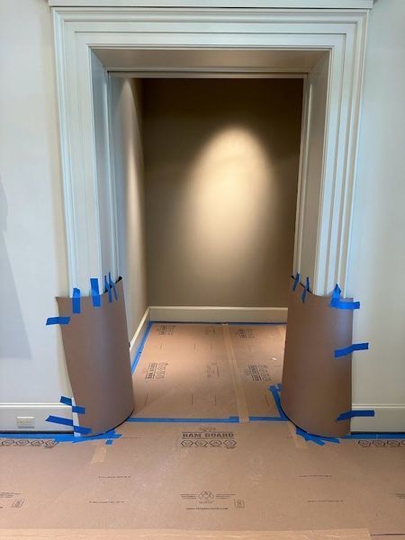 Brown paper floor protection in front of an open doorway with cardboard side protectors held with blue tape.