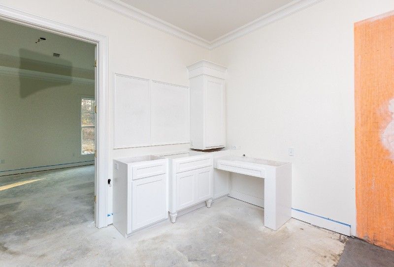 White cabinets in a room with unfinished concrete floor and a doorway.