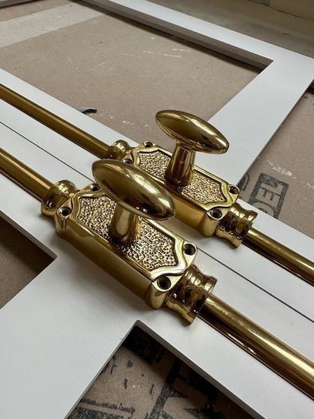 Two ornate gold door bolts mounted on white door frames.