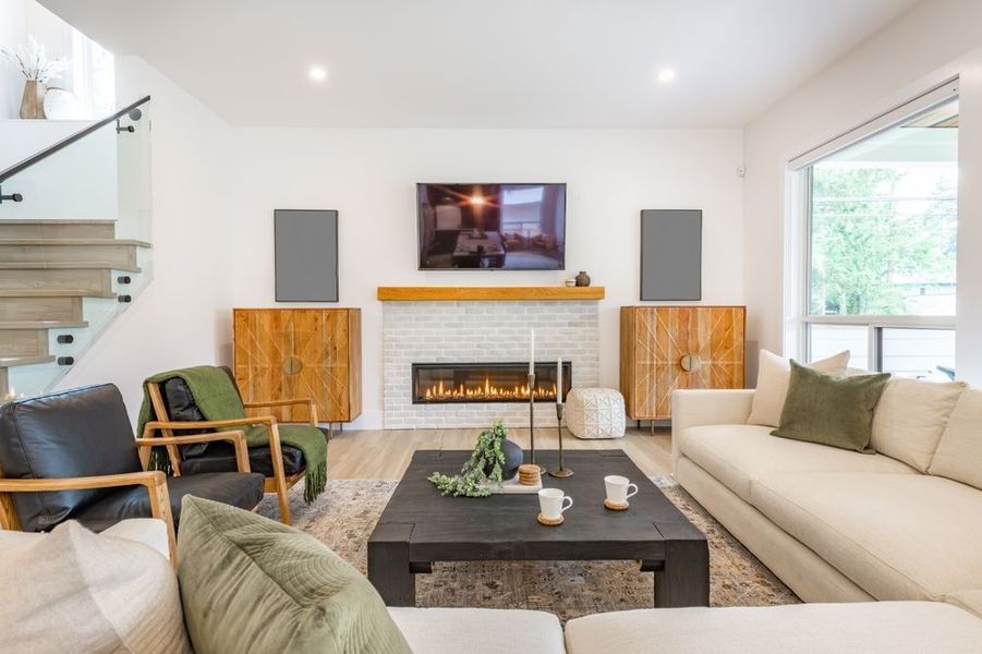 Living room with white walls, fireplace, and wooden furniture. A white couch faces the fireplace.