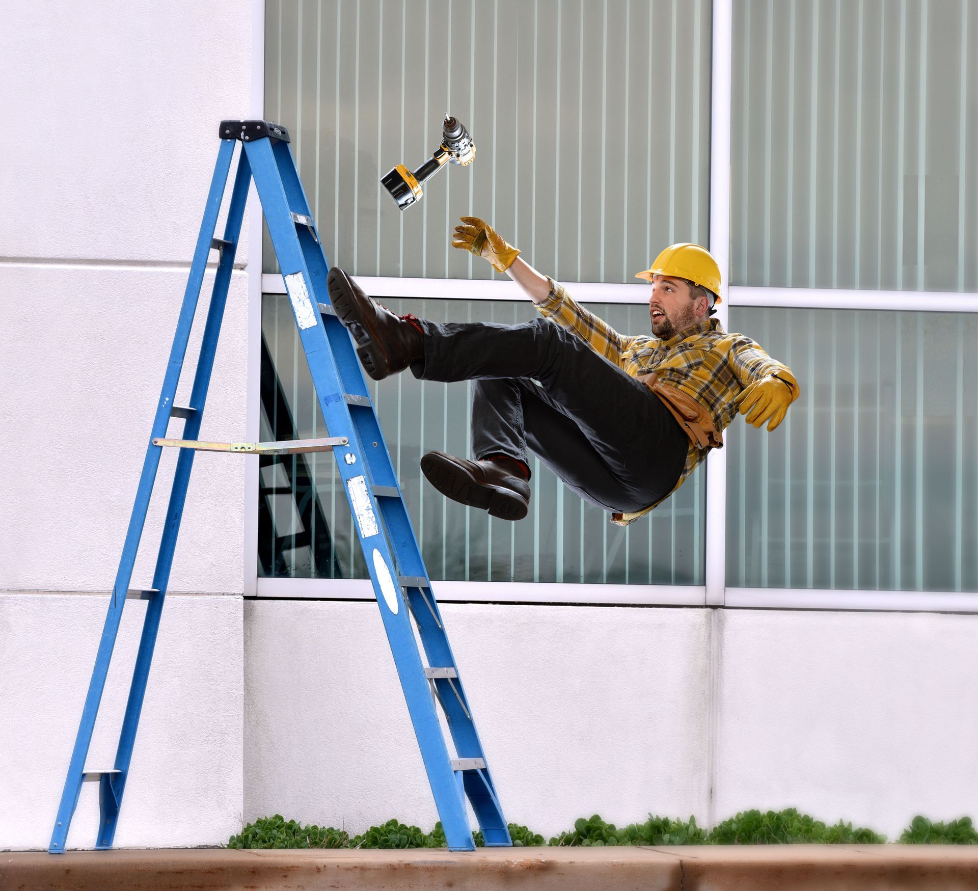 Construction worker falling from a blue ladder, dropping a tool.