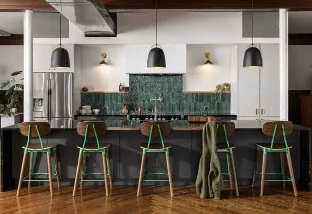 A kitchen with green stools and a black counter top