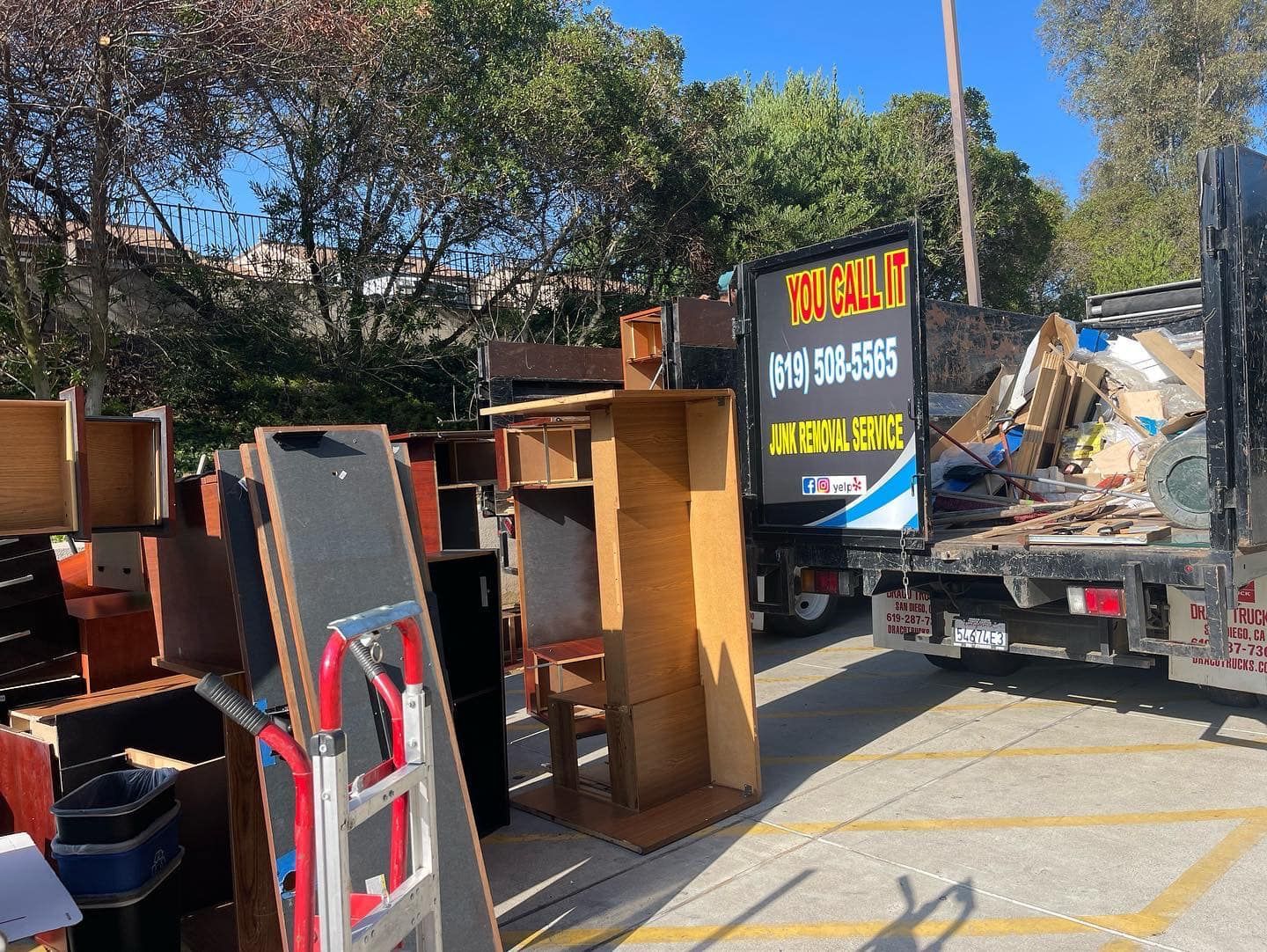 A truck being loaded with furniture, including cabinets and shelves, under a bright, sunny sky.