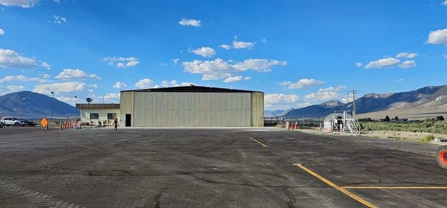 An airplane hangar with mountains in the background under a blue sky.