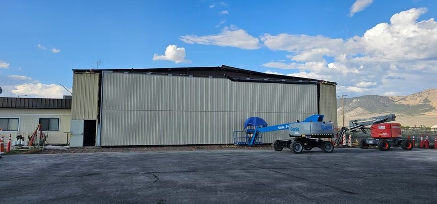 A damaged building with a damaged roof, a lift is in front of the building.