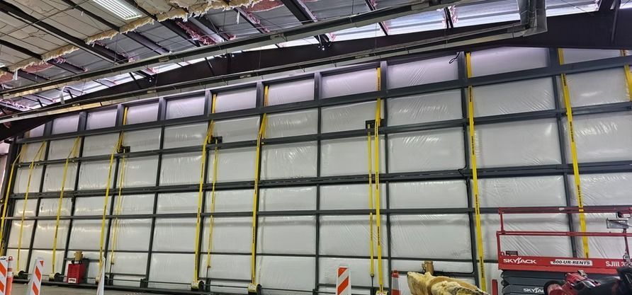 Large industrial door, white panels in metal frame, yellow support beams, red lift platform.