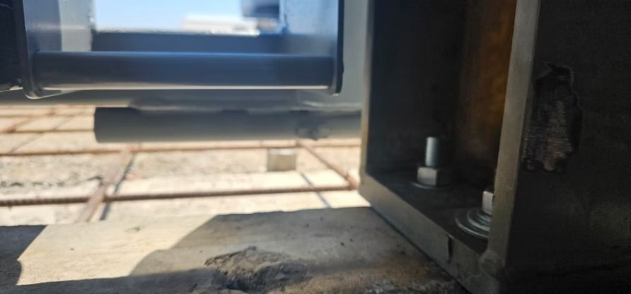 View from the window of a train over the railroad tracks, with metal bars and bolts on the window frame.