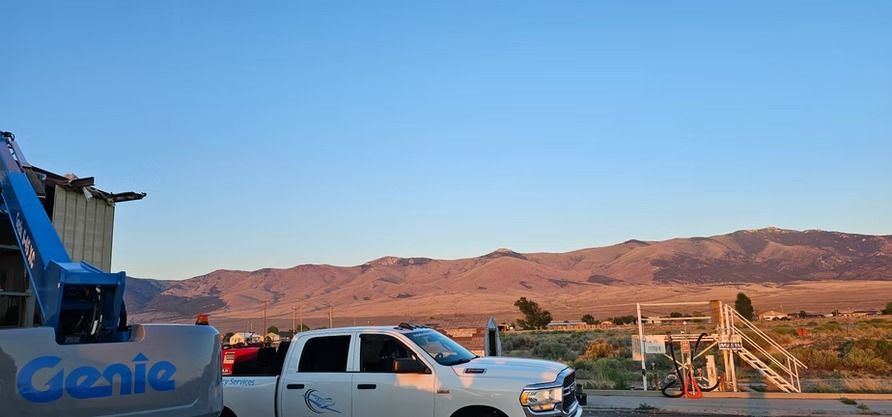 White pickup truck and blue lift with mountain range in the background under a blue sky.