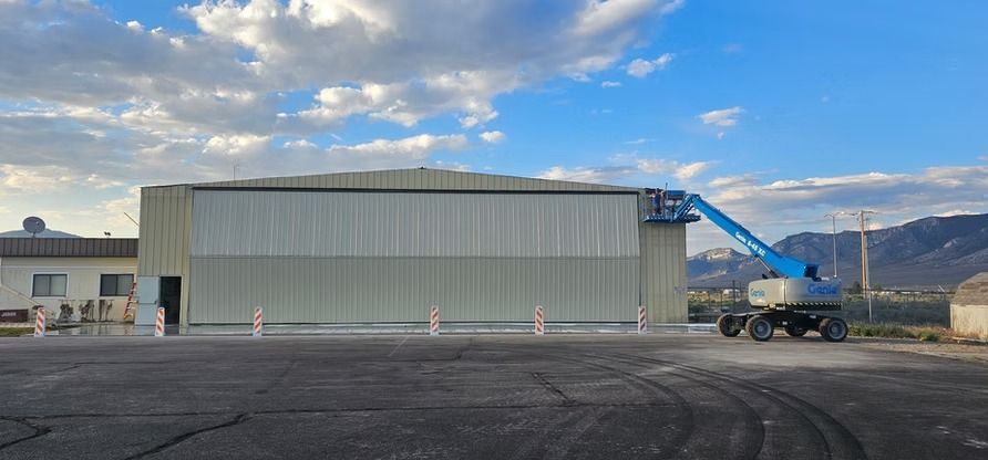 A large building with a blue lift in front of it. A person is in the lift, working on the side of the building.