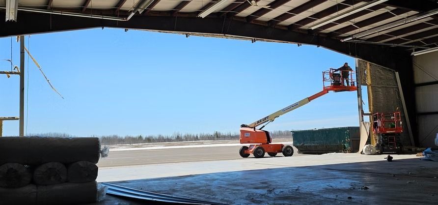 Worker on an orange lift outside a building, blue sky.