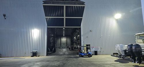 Exterior of a large boat storage building with a golf cart parked in front.