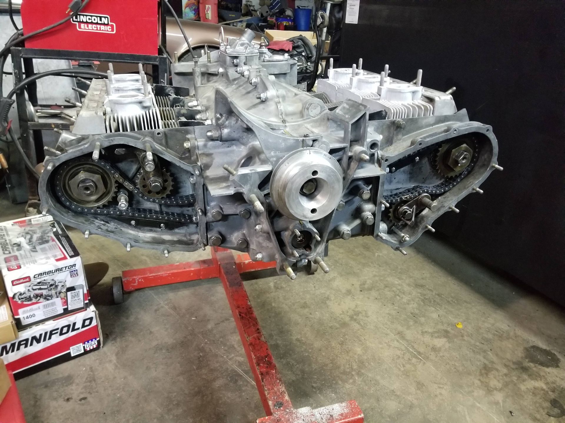 A car engine is sitting on a red stand in a garage.