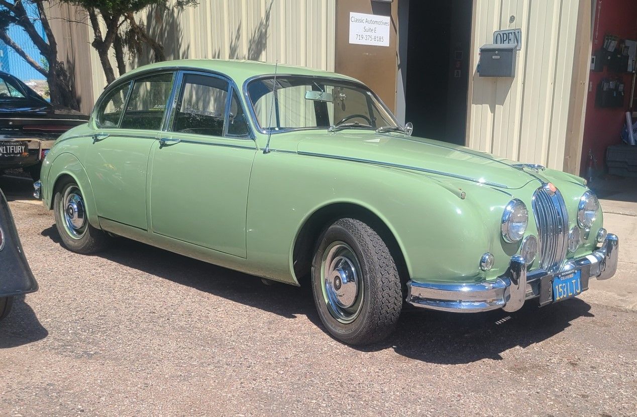A green car is parked in front of a building.