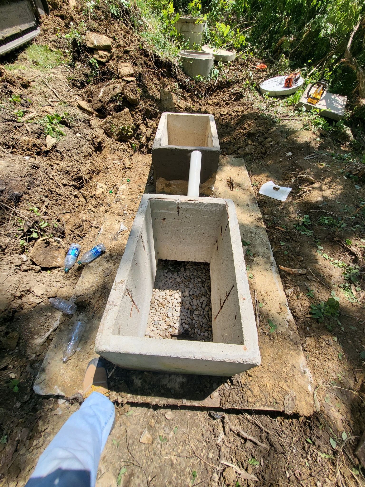Concrete septic tank components installed in an excavated trench in a yard setting.