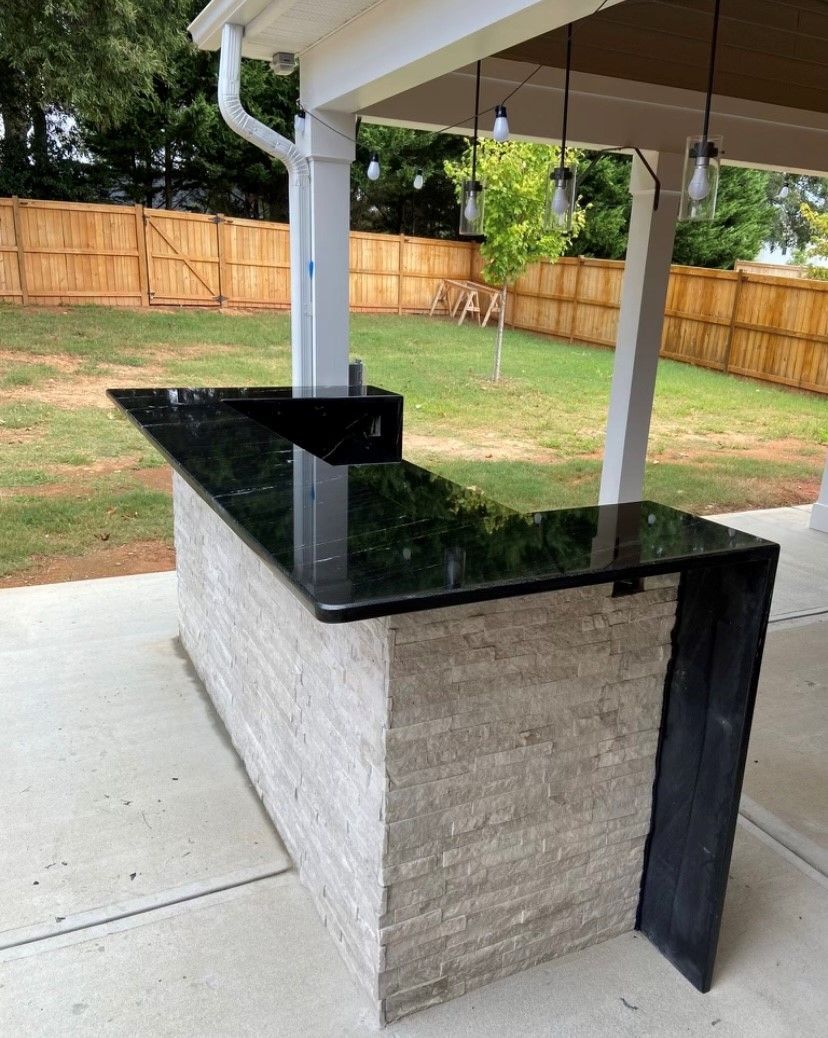 A patio with a black countertop and a wooden fence in the background