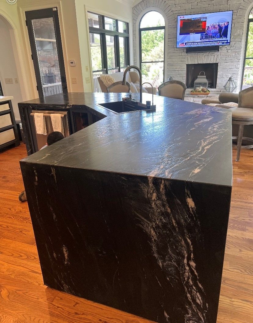 A kitchen with a large black granite island and a sink