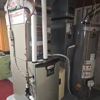 Furnace and water heater in a utility room with white pipes and ducts.