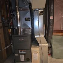 Furnace and ductwork in a basement setting. Gray and beige tones, with labels and pipes.
