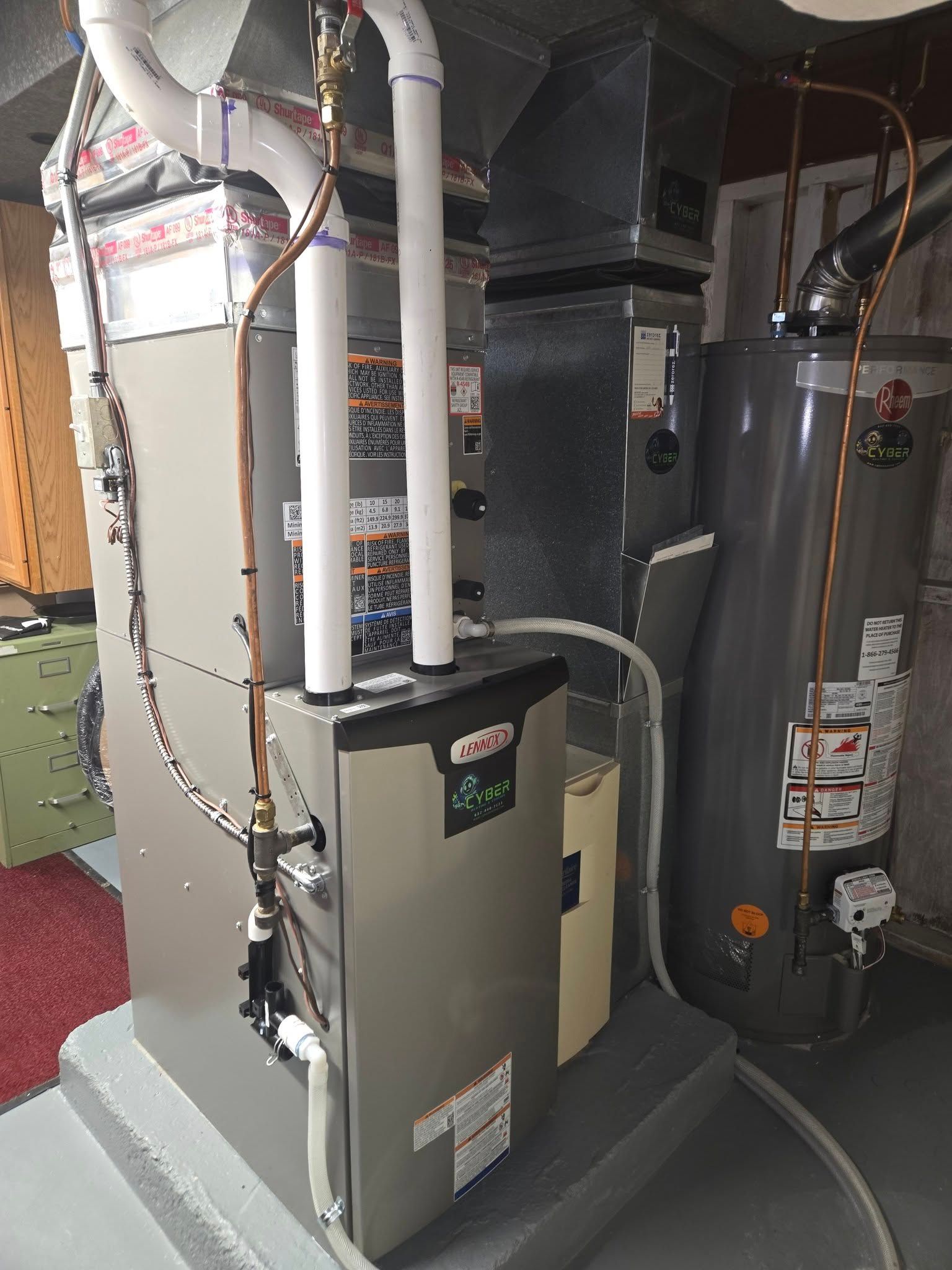 Furnace and water heater in a basement setting; gray and white appliances with connected piping.
