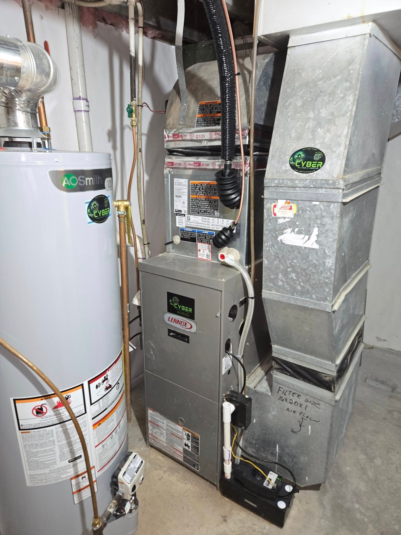 Furnace and hot water heater in a basement. Metal units with connected ductwork and pipes.